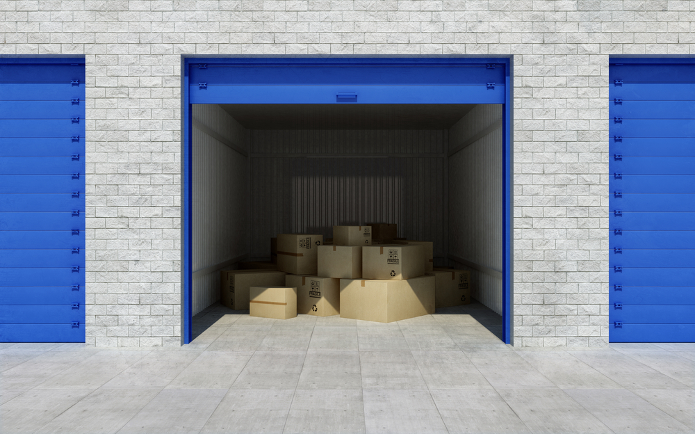 An opened storage unit with a blue doorway that is filled with cardboard boxes.