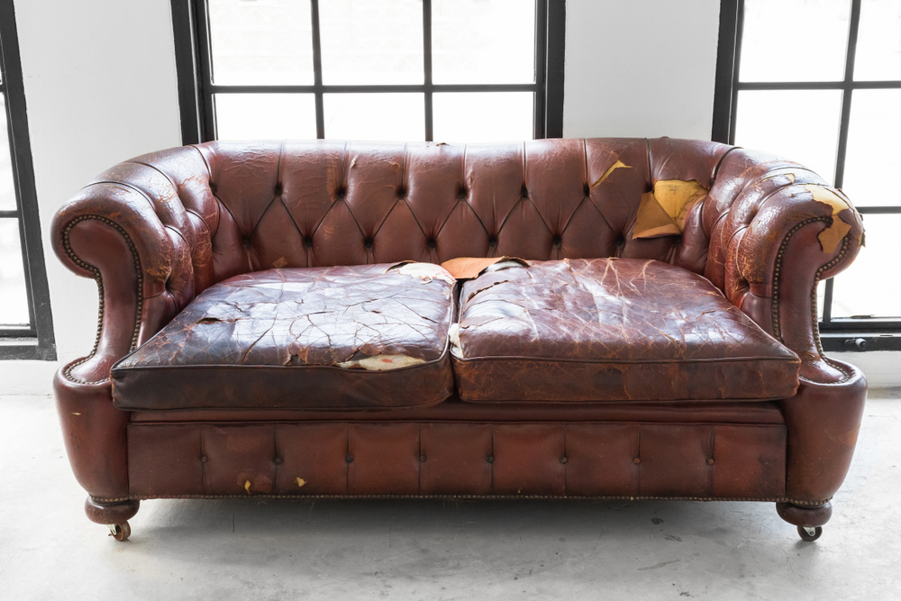 A couch that looks discolored and tattered from years of use