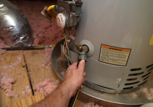Hand attaches hose to an old water heater