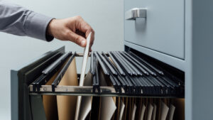 An office worker searching for files within a filing cabinet drawer