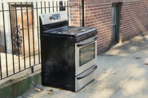 Closeup of a steel stove that has been thrown out on the sidewalk